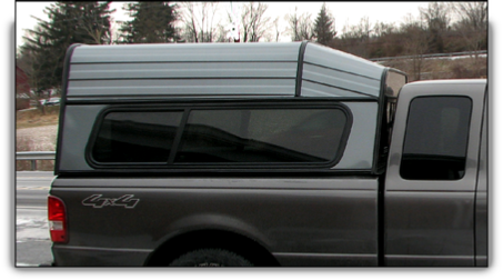 Ranger aluminum truck cap with drop front roof style and glass/awning/glass side windows.